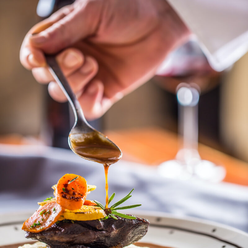 Chef decorates portion of the meal in pup or restaurant.