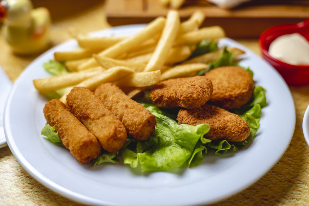 side view chicken sticks with nuggets and french fries on lettuce leaf